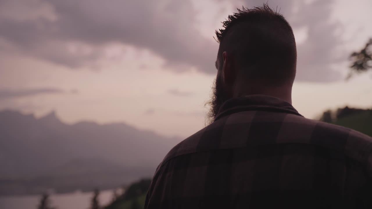 A man gazes toward the mountains at sunset, surrounded by calm nature and soft light. Concept of reflection, solitude, mindfulness, and connection with the natural world