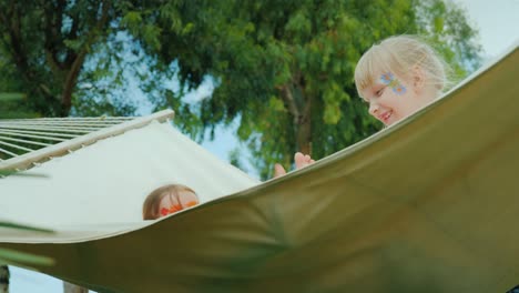 two children with painted faces play fun on a hammock, laugh and enjoy the holidays