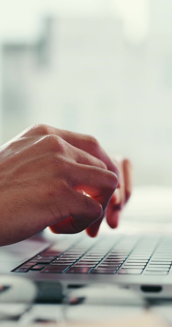 Close-up of Person Typing on Laptop Keyboard in Office