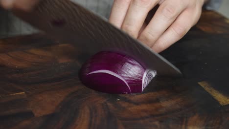 slicing onion with big kitchen knife on cut board in home kitchen