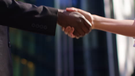 close up of businessman and businesswoman shaking hands outside offices in the financial district of the city of london uk