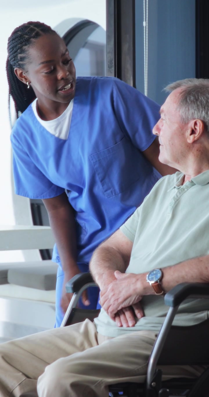 Young Nurse Talking to Senior Man in Wheelchair