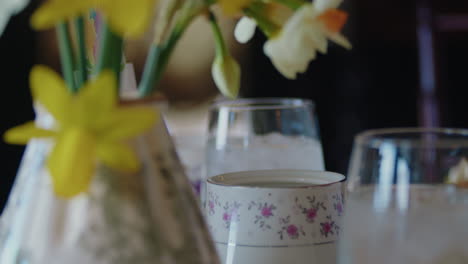 tight shot of silver tongs grabbing a sugar cube from fine china