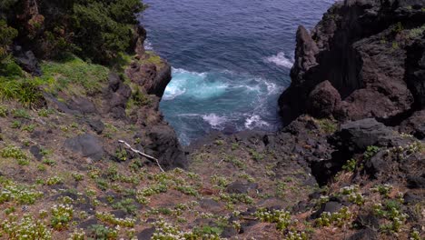 Rocky-Cliffs-With-Blue-Ocean-Waves-Breaking-On-The-Rocks-On-A-Sunny-Day---wide-shot