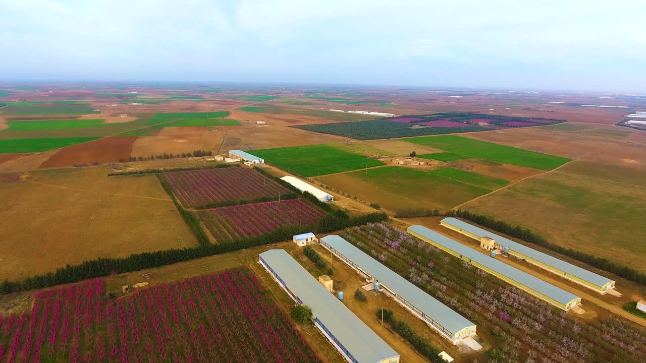 tomada aérea de un avión no tripulado de tierras de cultivo aradas con invernadero al atardecer
