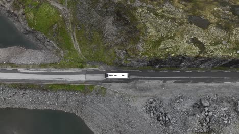 White-bus-crossing-Vikafjellet-mountain-pass-during-summer---Top-down-birdseye-aerial-following-bus