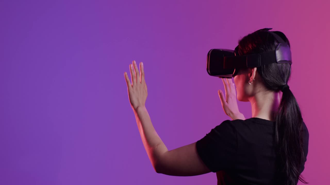 Asian woman using vr headset, touching screen on purple background, copy space, slow motion