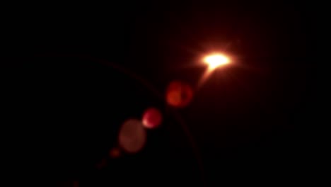 brillo naranja color cálido efecto de elemento de inflamación de la lente de luz que aparece a la izquierda y desaparece a la derecha en fondo negro. 4k movimiento de bucle sin costuras lente óptica inflamación efecto de superposición de transición.