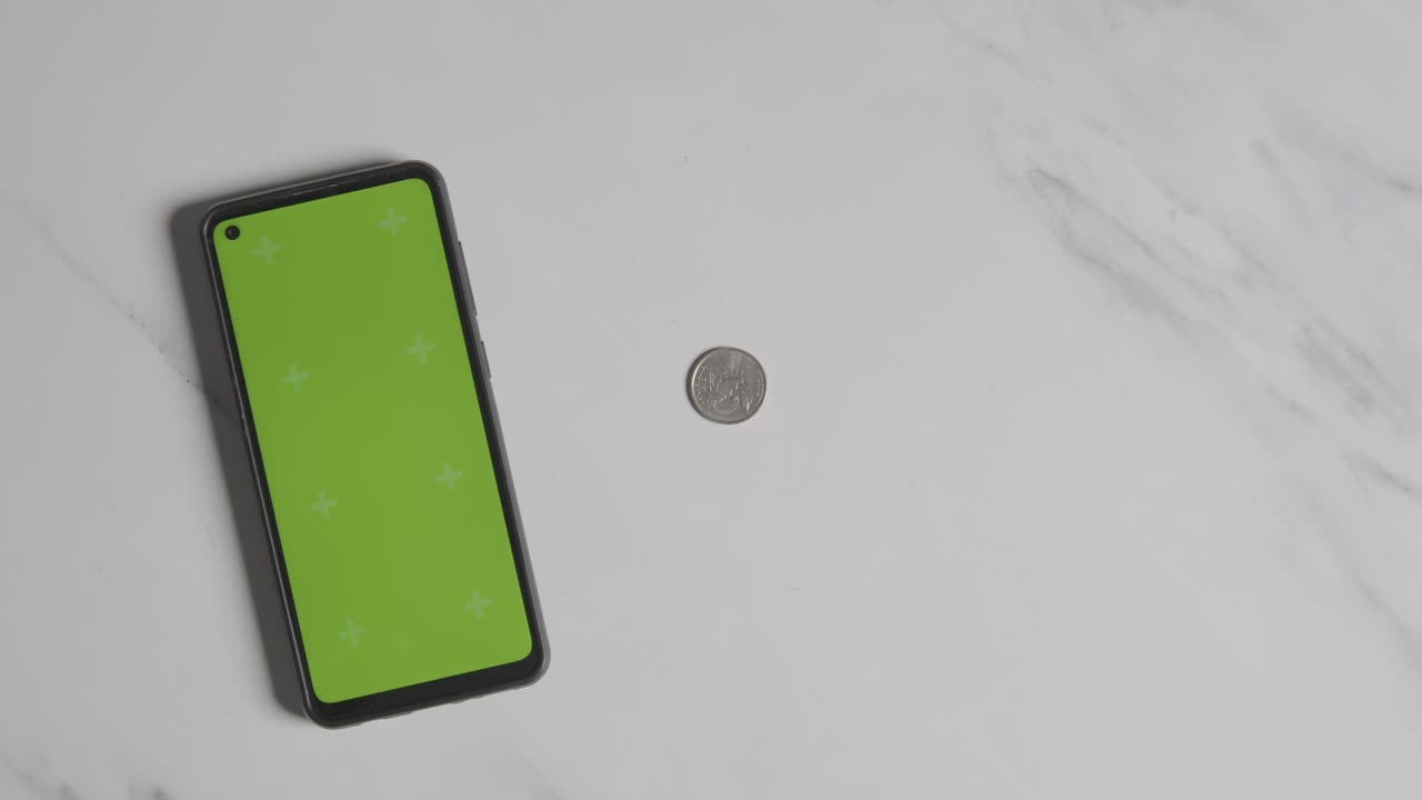 persona que agarra billetes y monedas de euro junto a un teléfono móvil de pantalla verde