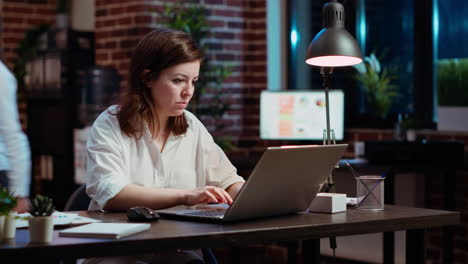 Office-clerk-looking-through-financial-business-documents-on-laptop