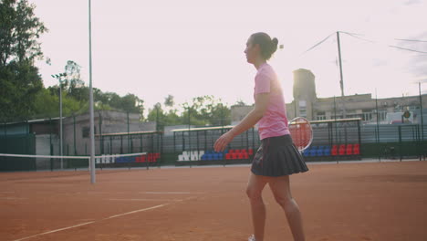 side view of a young caucasian woman playing tennis on a court returning a ball in slow motion