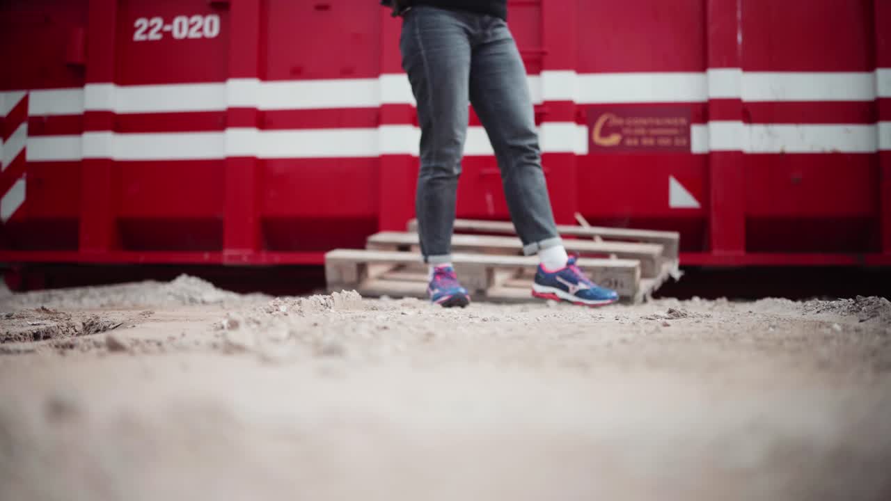 Girl in grey jeans waiting impatient in front of red container in copenhagen