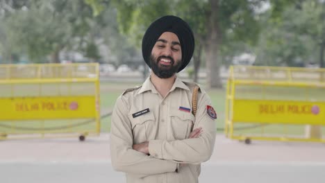 happy sikh indian police man standing crossed hands