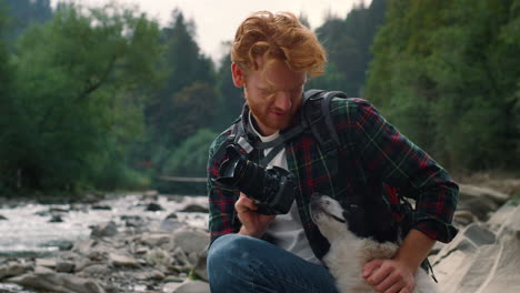 happy guy petting dog outdoor. smiling hiker enjoying natural landscape