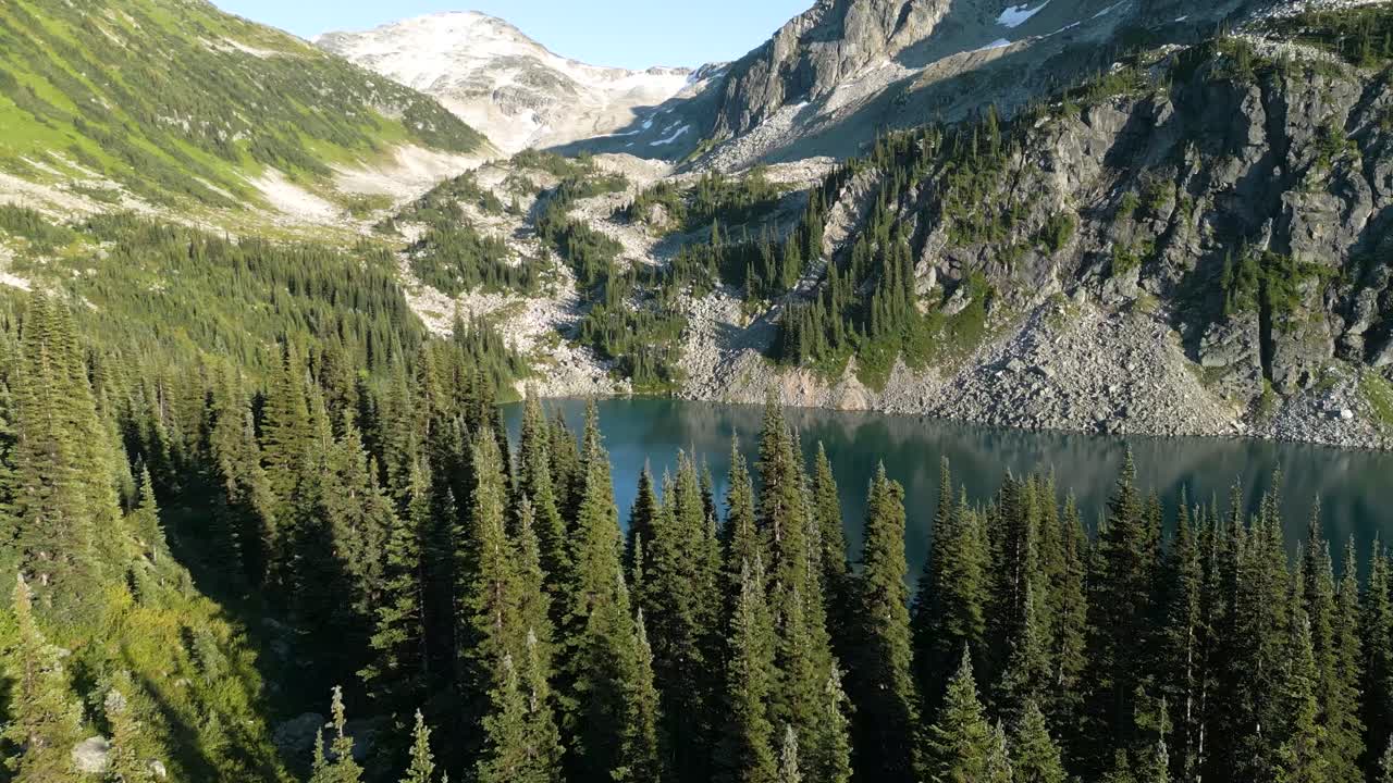 revelando un lago azul detrás del bosque de abetos con montañas al fondo