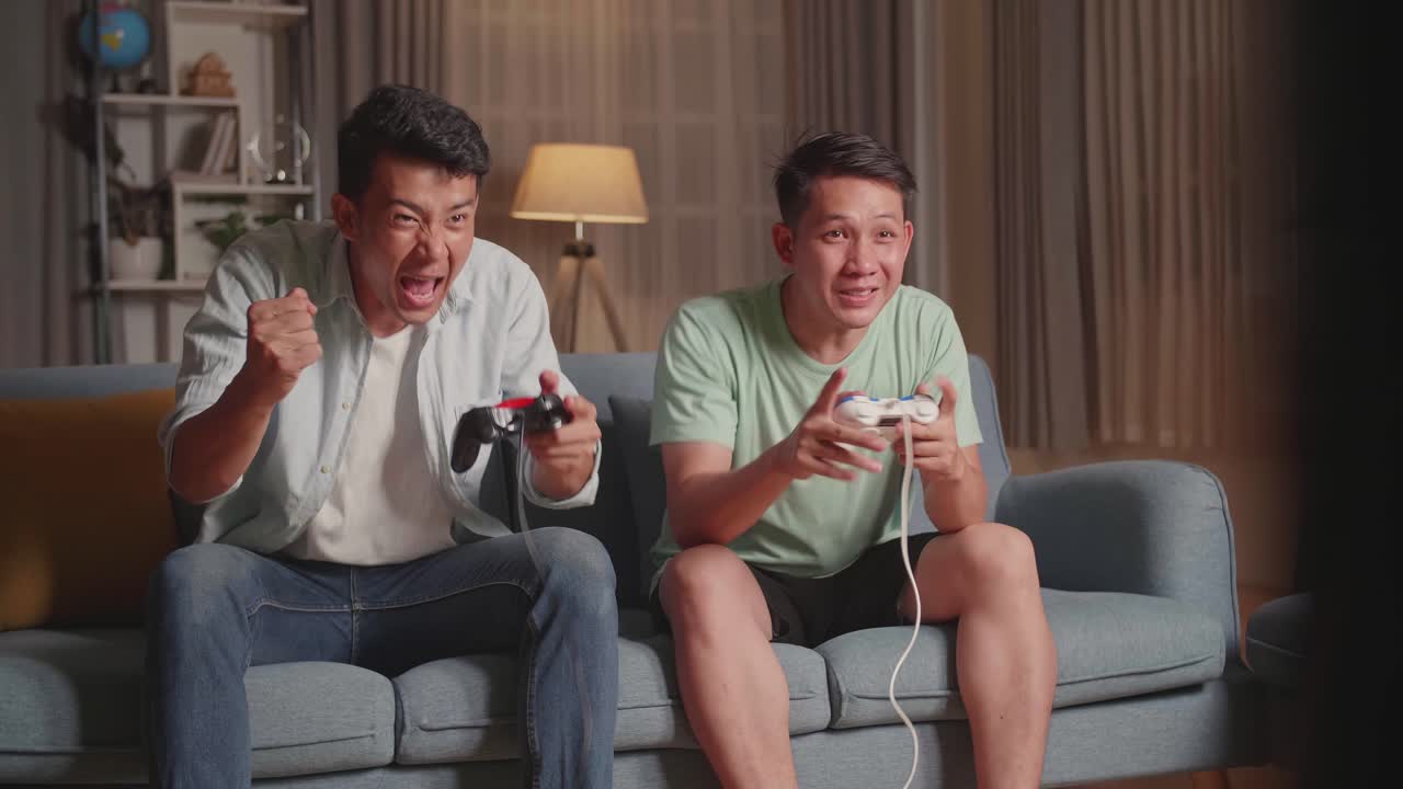 Asian Friends Playing Video Games And Celebrating Victory At Home