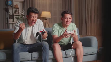 asian friends playing video games and celebrating victory at home