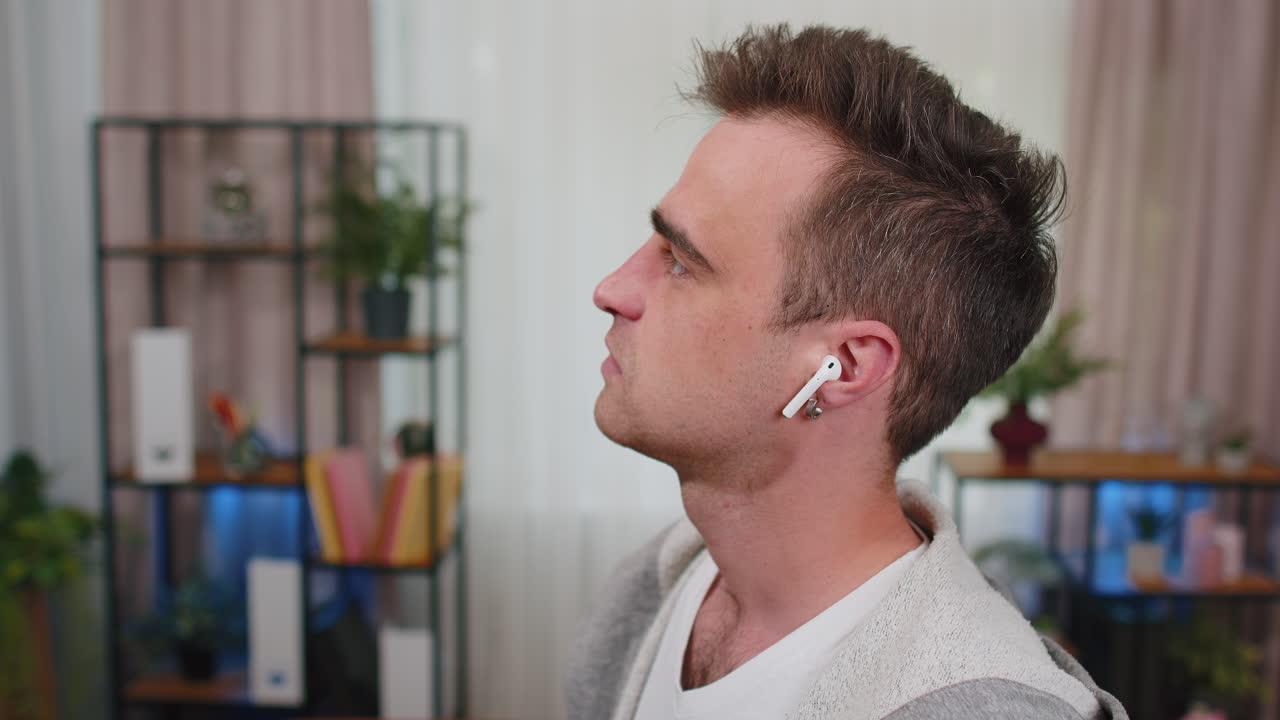 hombre feliz y relajado con auriculares inalámbricos bailando, escuchando su música rock n roll favorita en casa