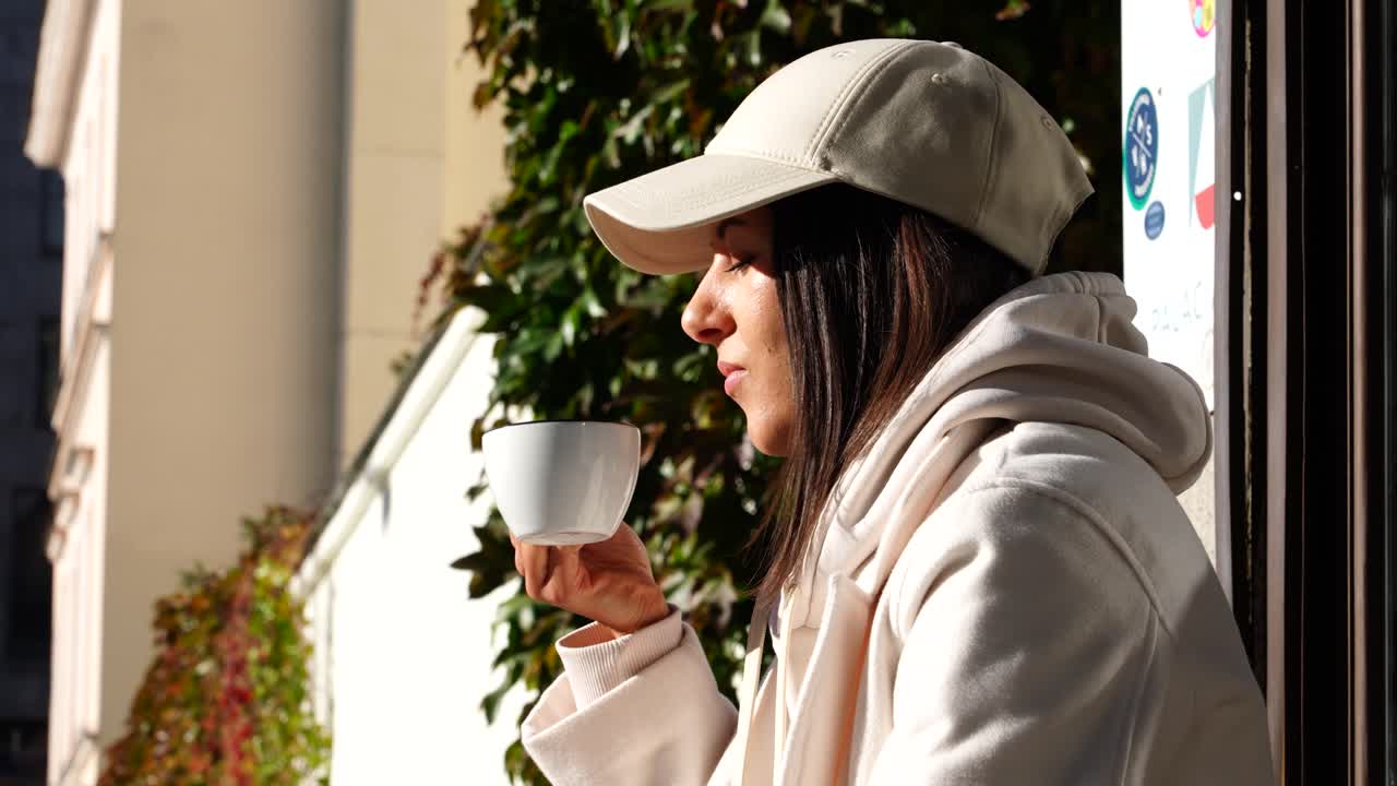 mujer relajada disfruta de una taza de café por la mañana frente a la luz del sol brillante en una cafetería al aire libre