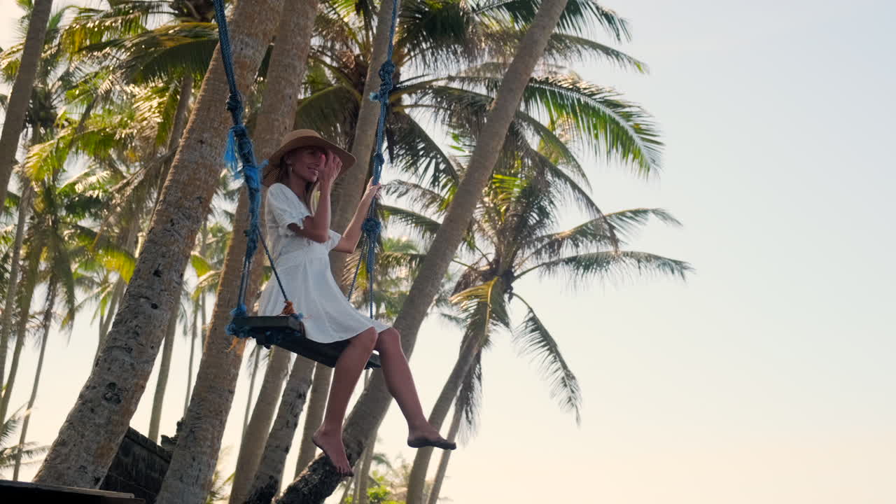 mujer balanceándose en un columpio en las palmeras