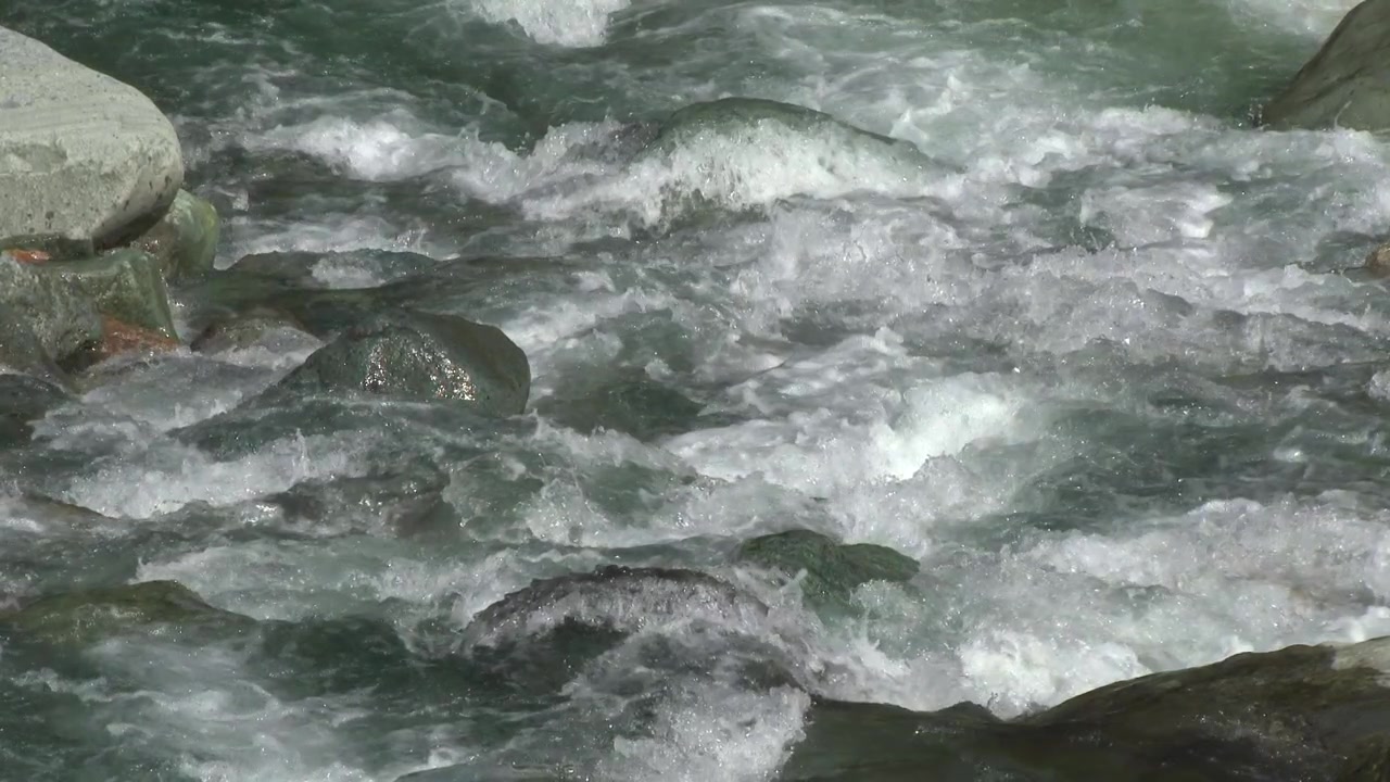 Acqua di fiume di montagna che scorre velocemente sopra le rocce