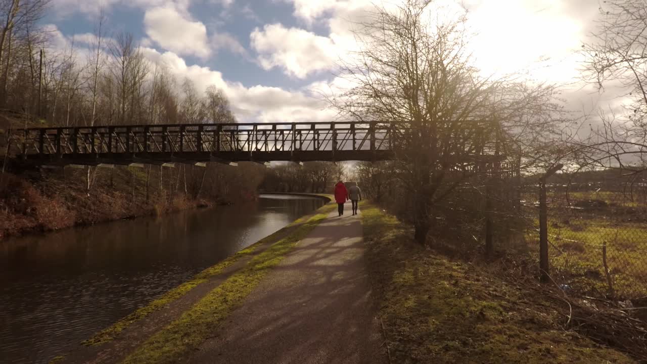 2 women take a walk along by the former industrial canal in Stoke on Trent, a poverty stricken area featuring many factories in ruins along by the canal