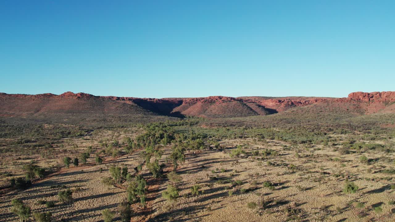 Rising drone footage of landscape with Kings Canyon, Watarrka in the distance, Northern Territory, Australia. August 2022.