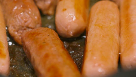 delicious vegan plant based protein sausages in bubbling hot oil. carbon friendly meat alternative food cooking in frying pan. processed with natural ingredients