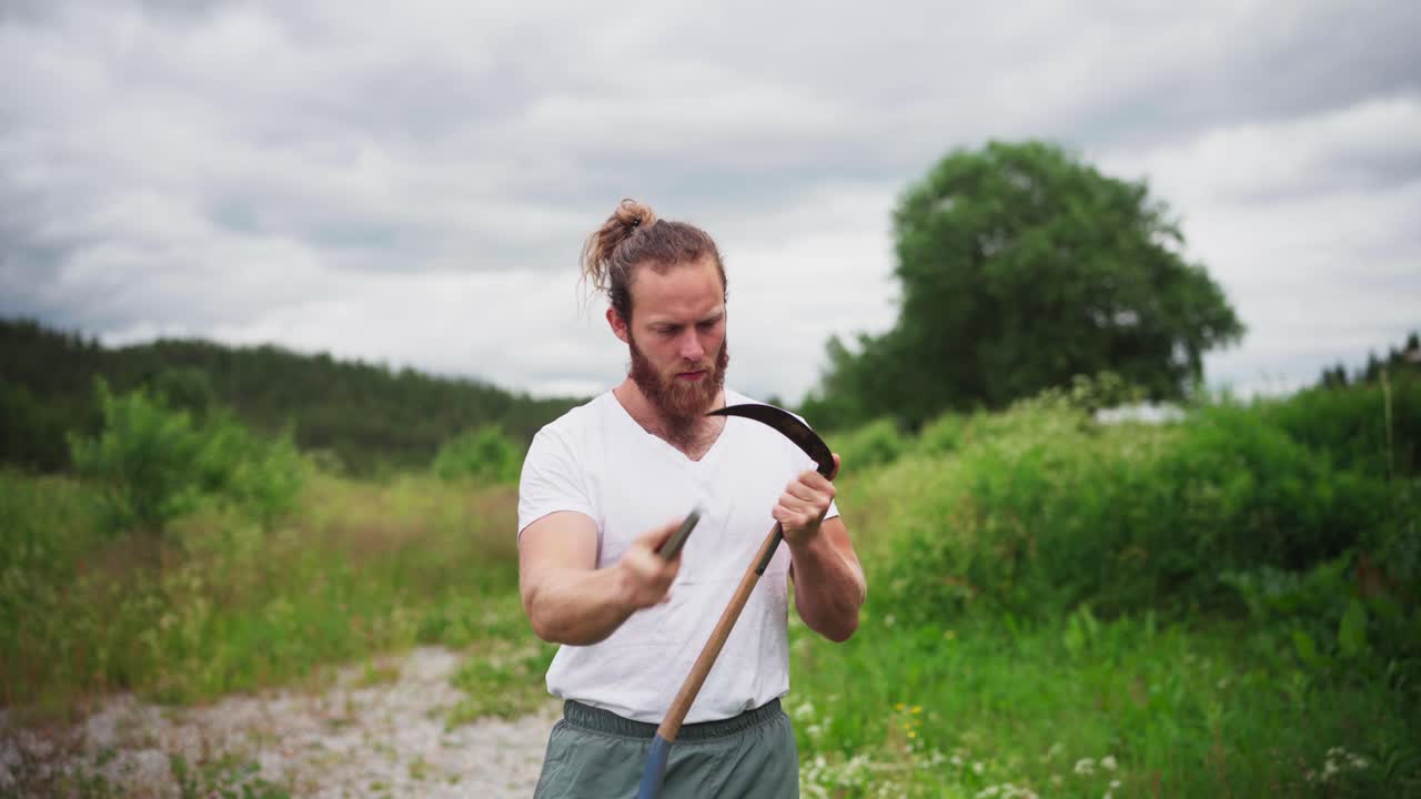 Man Sharpening Blade Of A Scythe With Sharpening Stone Outdoor