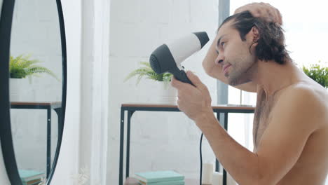 hombre secándose el cabello en el baño