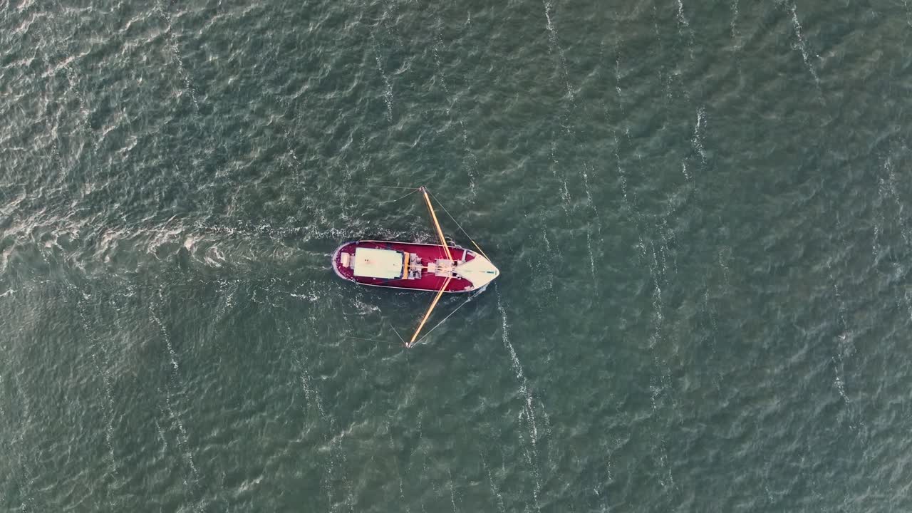 Dronebilde ovenfra av en fiskebåt som drar garnene gjennom vannet