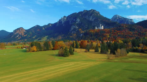 drone view slowly lifting up over scenic autumn field with a distant castle on hill in the afternoon near the neuschwanstein castle in germany, europe, wide view