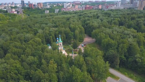 aerial view of a church in a forest with city in the background