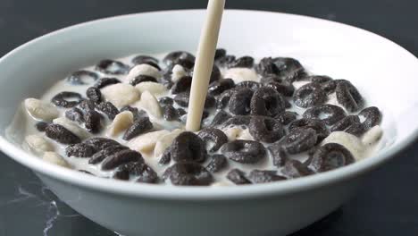 pouring milk into a bowl of chocolate cereal