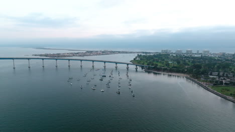 Toma-Panorámica-Aérea-Sobre-La-Bahía-De-San-Diego,-Puerto-Deportivo-De-La-Isla-Coronado-Cerca-Del-Hermoso-Puente-Curvo-En-El-Fondo