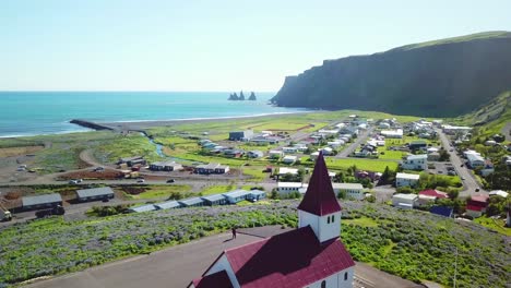 Toma-Aérea-De-Establecimiento-De-La-Ciudad-De-Vik,-En-El-Sur-De-Islandia,-Su-Icónica-Iglesia-1