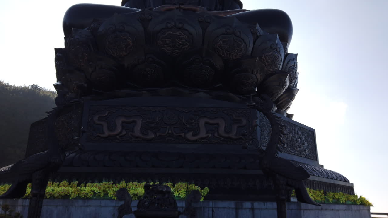Panning shot around massive Buddha, pan ends in sunlight hitting lens, backlit, gimbal, Fansipan, SAPA, Vietnam