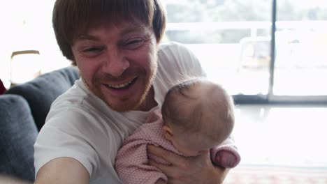 Joyful-dad-holding-baby-daughter-and-taking-video-selfie