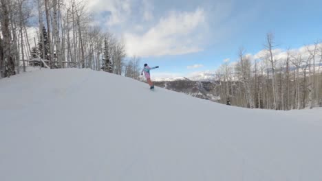 Fast-female-snowboarder-riding-down-white-slope-Onn-sunny-day