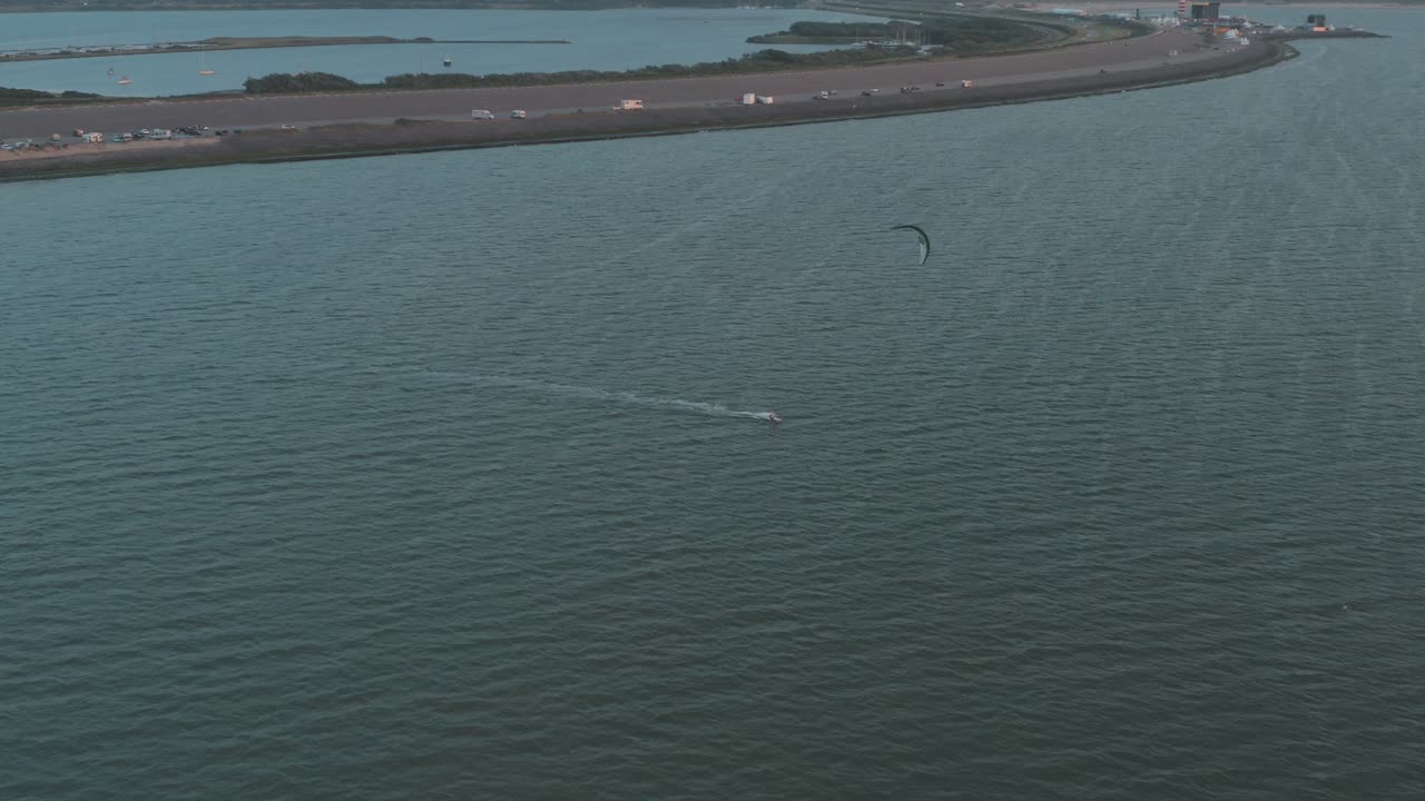 Cinematic drone - aerial panorama circling shot a windsurfer at sunset with tourists and people at Zeeland at the north sea, Netherlands, 25p