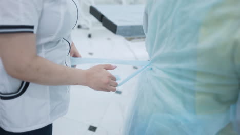 nurse assisting in putting on protective gown