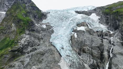 glaciar boyabreen vista detallada de cerca con el derretimiento del glaciar corriente de agua que fluye hacia abajo en el lado derecho - aero de fjaerland parte del glaciar jostedal noruega - 60 fps