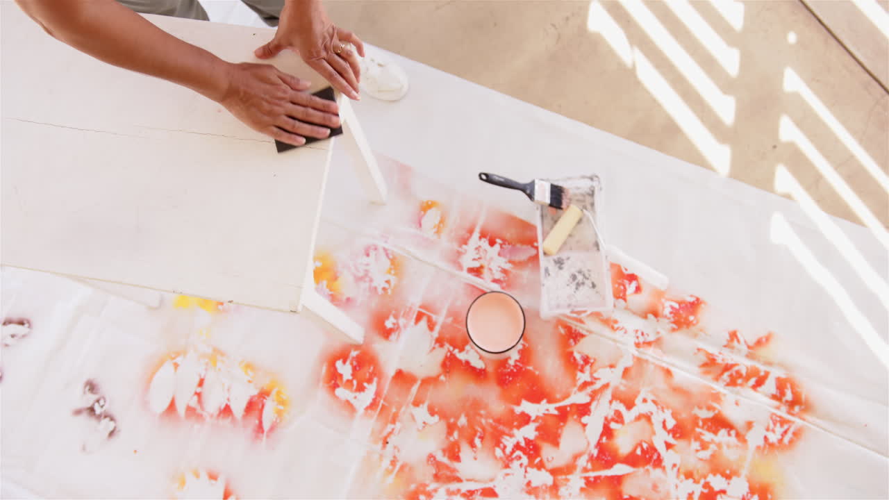 Painting on canvas, person using brush and paint cans for creative artwork