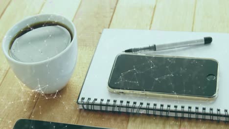 animation of network of connections and digital icons against office equipment on wooden surface