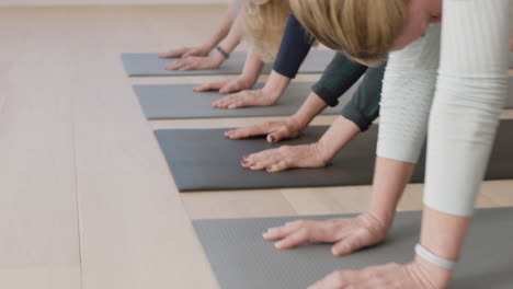 close up hands yoga class of mature women exercising healthy meditation practice downward-facing dog pose enjoying morning physical fitness workout in studio