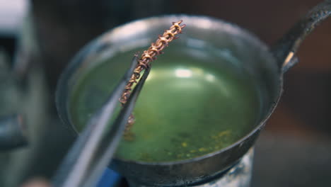 jeweler-puts-gold-chain-into-boiling-green-liquid-closeup