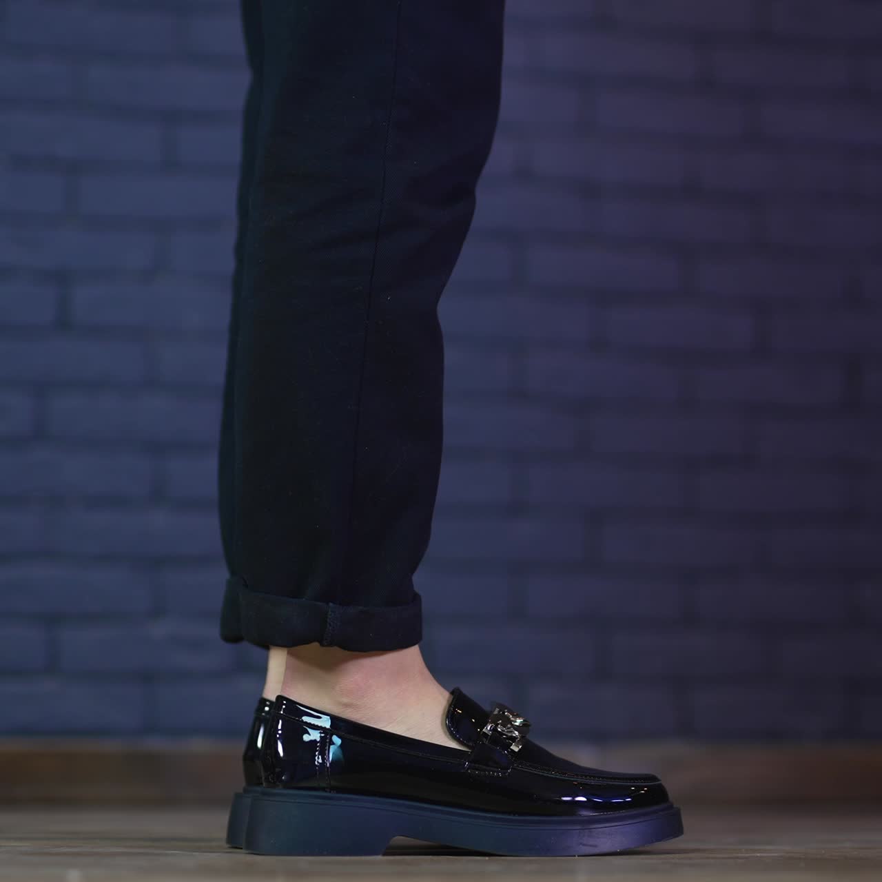 Female model in black beautiful lacquered shoes jumps up to stand on toes. Fashionable designer footwear demonstration. Close up