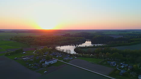 a smooth shot of a small sunset neighborhood landscape with a lake and a forest