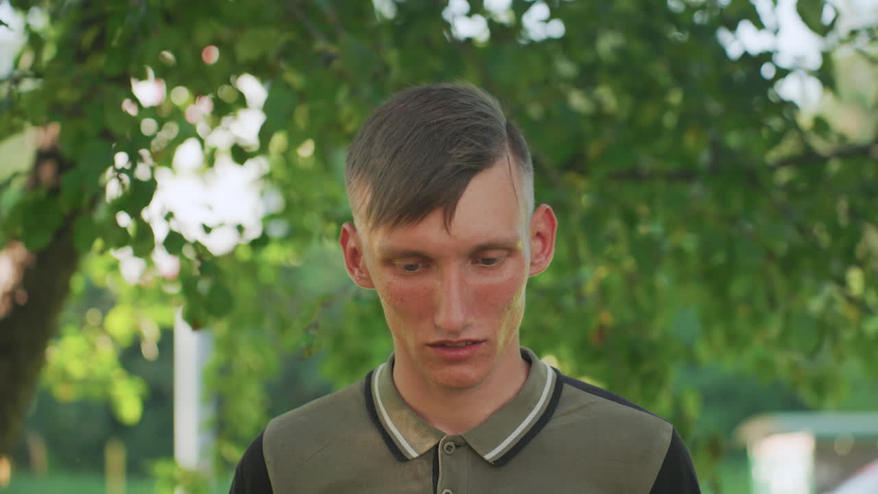 White Teen Frontal Portrait In Park, Defiant Glare And Tense Posture Under Leafy Canopy, Summer Light And Gritty Urban Edge Convey Rebellious Mood, Raw CloseUp Of Youth Tension And Possible Paranoia