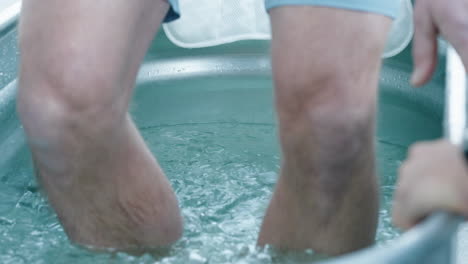 unidentified caucasian man gets into a steel bathtub filled with ice cubes trying the wim hof ice bath experience